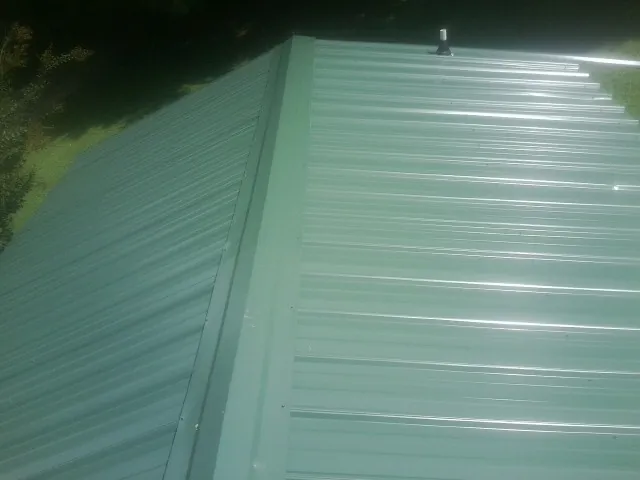 New green metal panels meeting at the ridge of a roof — Flat Roof Repair work by our crew in Amissville