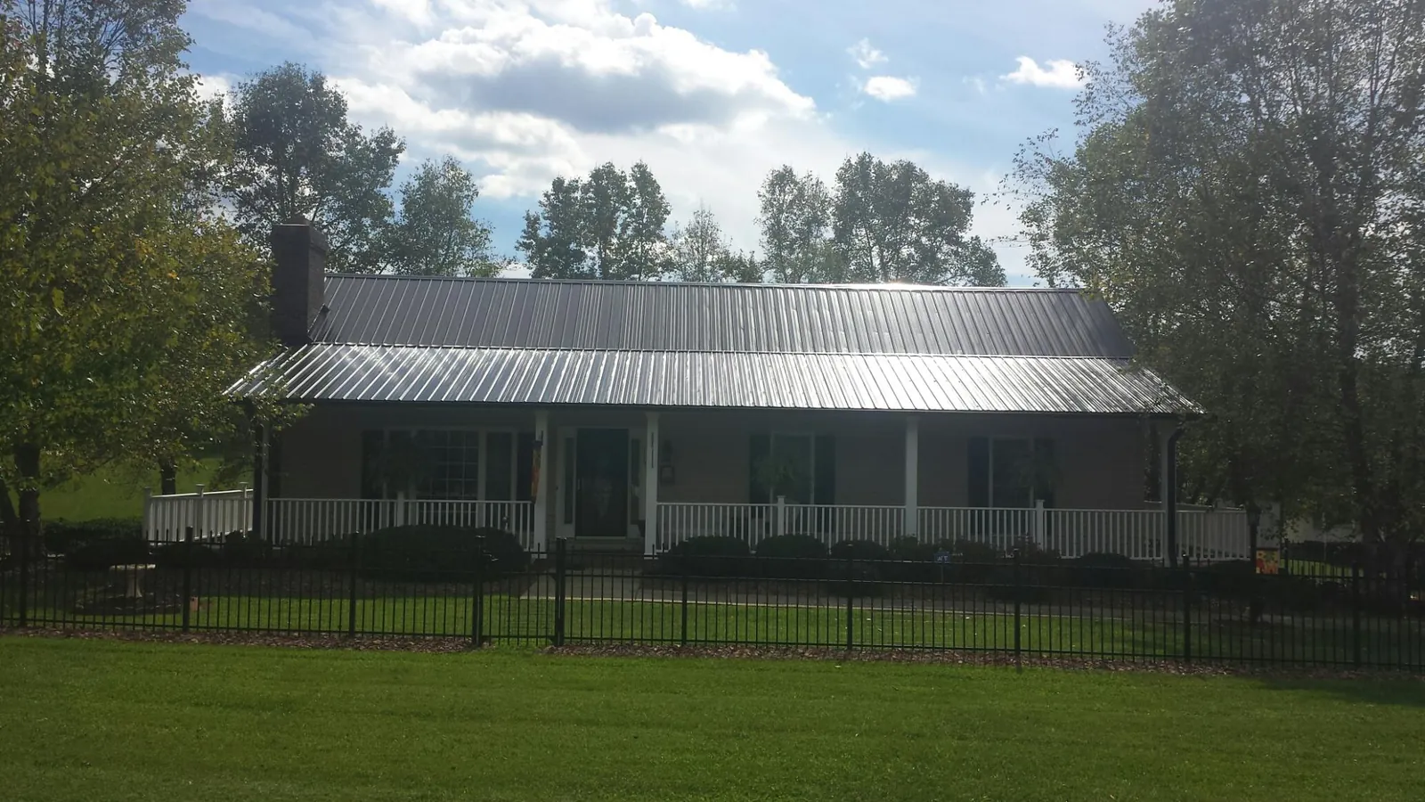 Gray metal roof on a brick ranch with a full width front porch — Gutter Guard Installation work by our crew in Amissville