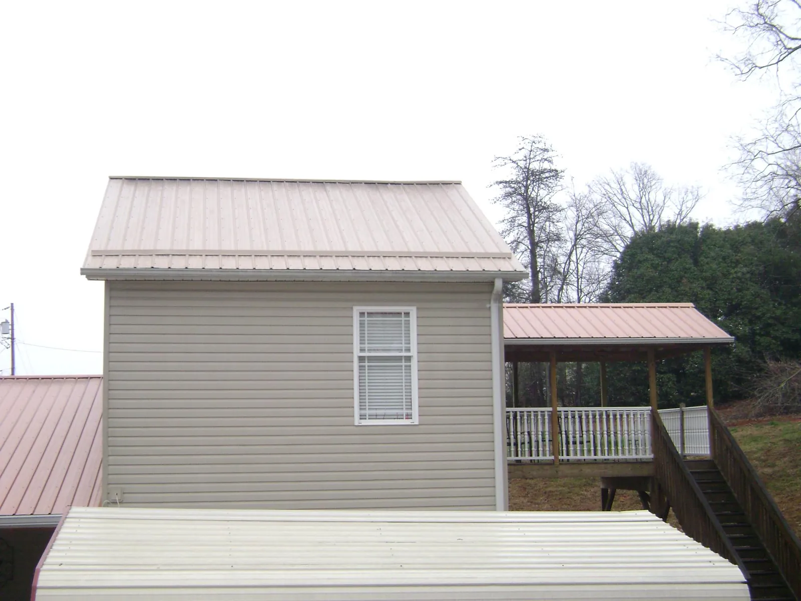 Tan metal roofs on a two story addition and attached porch, from a Roof Replacement job in Amissville
